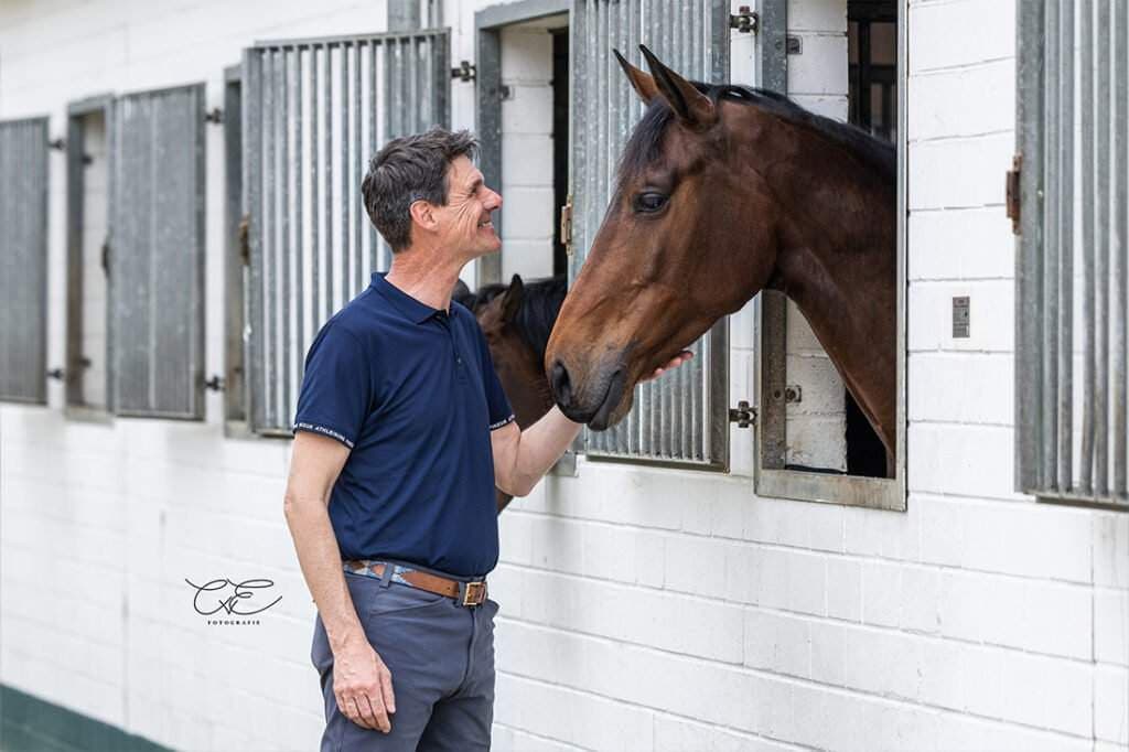 Dieses Bild zeigt einen Mann, der eine braune Stute streichelt.